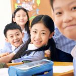 Happy schoolchildren in class wearing uniforms, engaging in studies and posing for a photo.