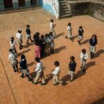 Aerial view of children playing a game on the school courtyard during daytime.